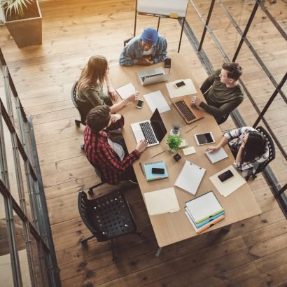 Top view happy women and satisfied male talking while having job with gadgets in office. Friendly start-up team concept