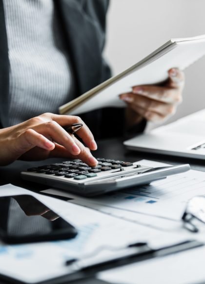 Close up of businesswomen or accountant using calculator calculate while working analytic business report on the workplace, Planning financial and accounting concept.