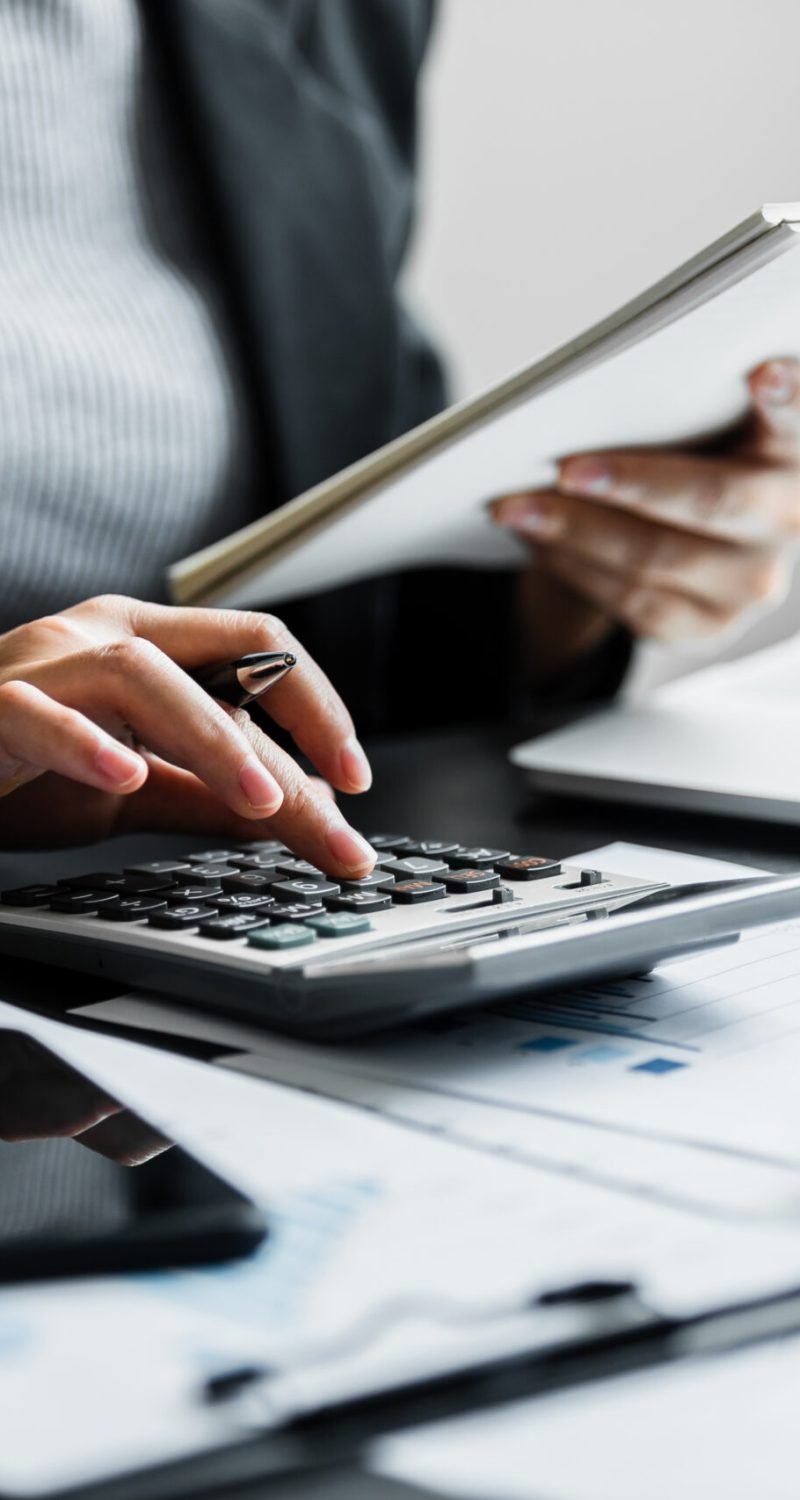 Close up of businesswomen or accountant using calculator calculate while working analytic business report on the workplace, Planning financial and accounting concept.