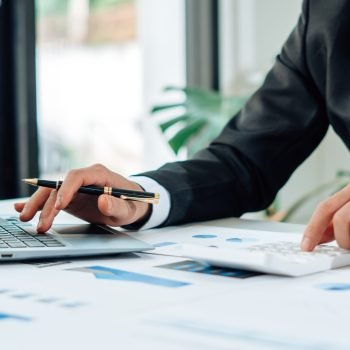 Close up of accountant or banker checking investment results, calculates financial savings, calculates annual taxes and economic concepts. Financial calculation concept.